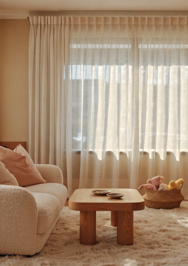 A warm family living room with a rounded-edge coffee table and a basket of baby toys